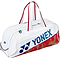 The Yonex 02631WEX Expert Tournament Badminton Bag in white features red accents, red handles, a blue Yonex logo, and a stylish red and gold base—perfect for tournaments.