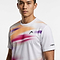 A man wears the HEAD Blur Mens Badminton T-Shirt - PUXU, a moisture-wicking tee with orange, pink, and purple blurred streaks, chest logo, and "HEAD" on the sleeve, standing against a plain white background.