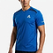 A man wears the Le Coq Sportif Pro Mens Badminton T-Shirt in Lapis Blue, featuring short sleeves, black mesh shoulder accents, and branded logos—ideal breathable sportswear from Le Coq Sportif for active days.
