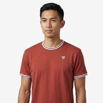 A man with short black hair wears a terracotta Tecnifibre Team Stretch Mens Badminton T-Shirt, featuring white trim and a small white logo, standing against a plain white background.