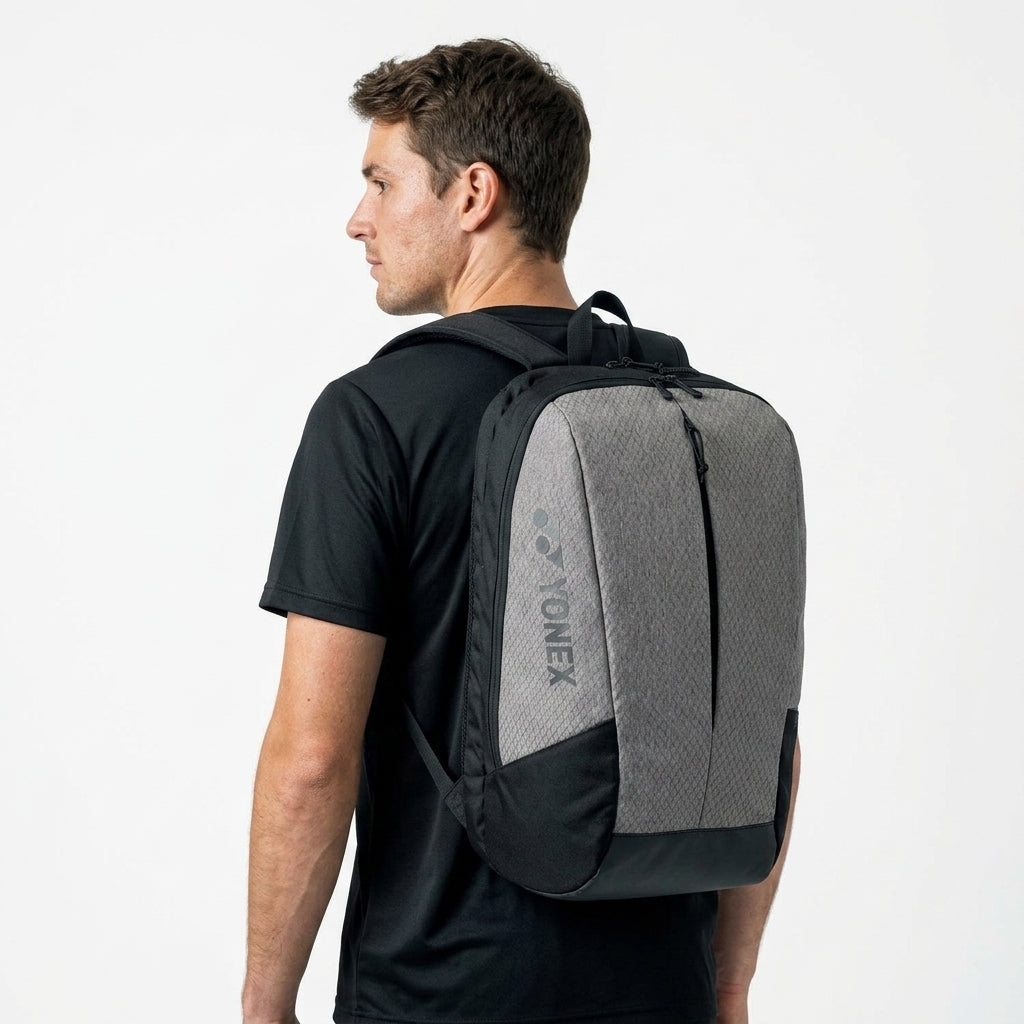 Man wearing a black and gray Yonex backpack on a white background