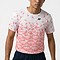 A person wears the Yonex YTM2025B Men’s Badminton T-Shirt in white, featuring a pink geometric floral pattern and small black logo, paired with dark shorts against a plain background.