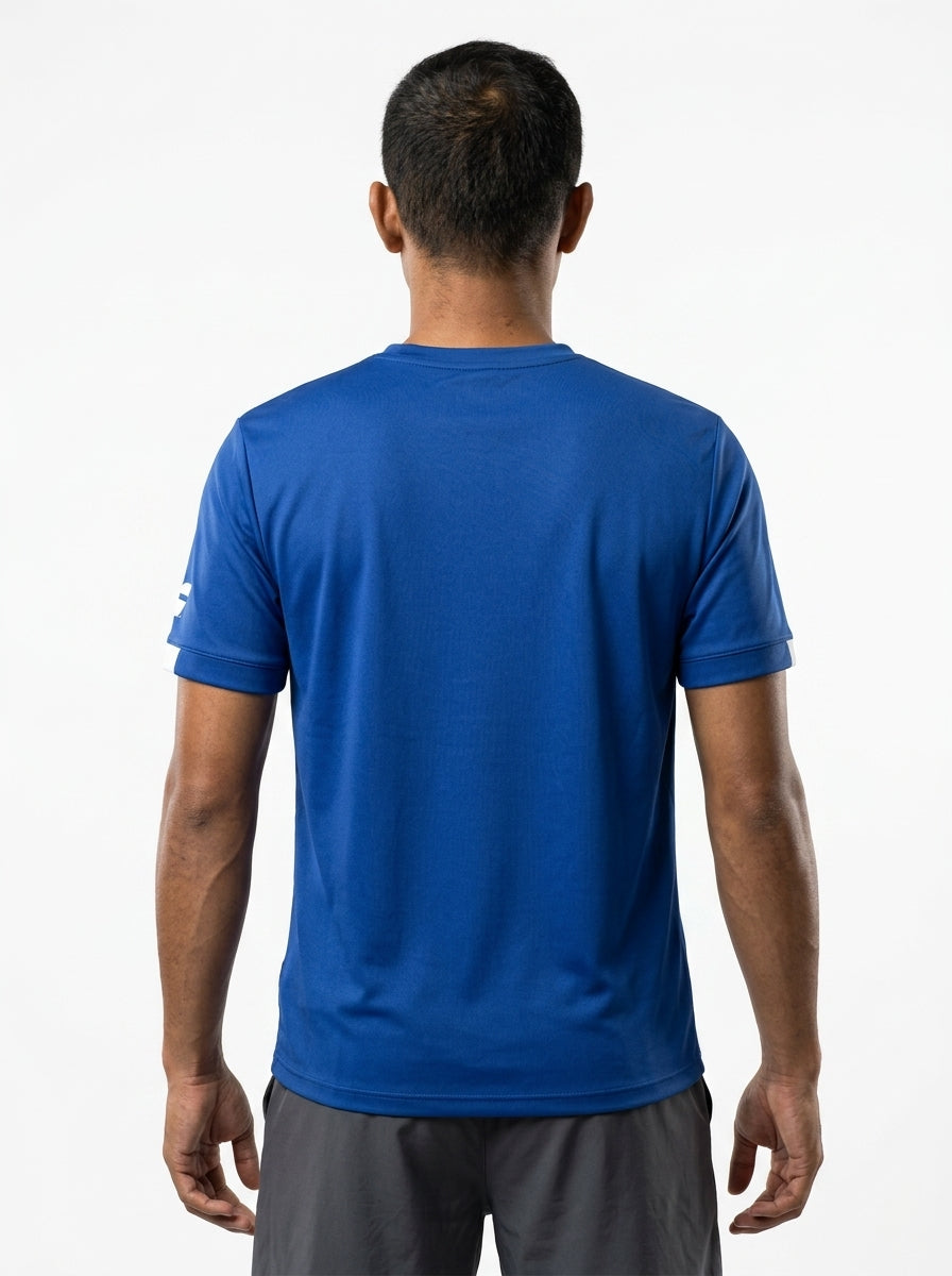 A man with short dark hair faces away, wearing the Babolat Play Men's Crew Neck Badminton T-Shirt in Sodalite Blue by Babolat and gray shorts, posed against a plain white background.