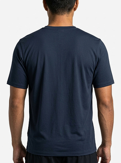 A person, facing away from the camera, wears a HEAD Simple Mens Badminton T-Shirt in navy and black shorts against a plain light background.