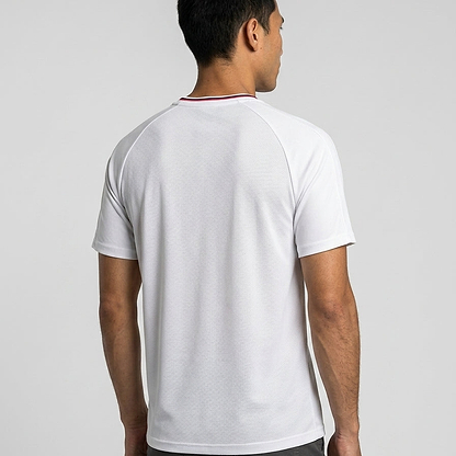 A man with short dark hair stands facing away, wearing the white K-Swiss Hypercourt Mesh Crew 4 Men's Badminton T-Shirt by K-Swiss, featuring modern performance sportswear style against a neutral gray background.