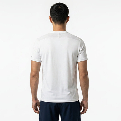 A man with short dark hair is seen from behind, wearing a Le Coq Sportif Pro Mens Badminton T-Shirt in Optical White and dark shorts against a white background—a stylish choice from Le Coq Sportif.