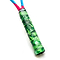 Close-up of a badminton racket handle wrapped with the Get A Grip Ace Tropic Green Overgrip, featuring a leaf-patterned design for excellent moisture absorption. The shaft above the non-slip grip is blue, and part of the pink racket frame is visible.