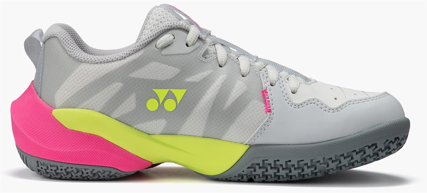 The Yonex Subaxia GT Women's Badminton Shoes in light grey feature white, gray, and light green tones with pink accents, a Yonex logo on the side, and a textured sole designed for grip with GRPHT THRTTL technology.