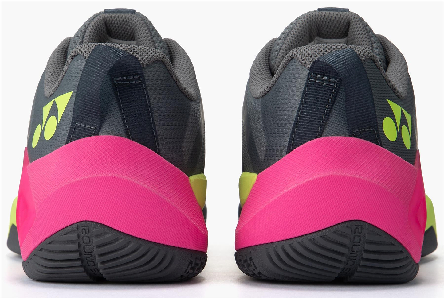 Rear view of the Yonex Subaxia GT WIDE Unisex Badminton Shoes in grey, featuring neon yellow Yonex logos, bright pink heels, and sporty soles with GRPHT THRTTL technology for superior grip and a modern athletic style.