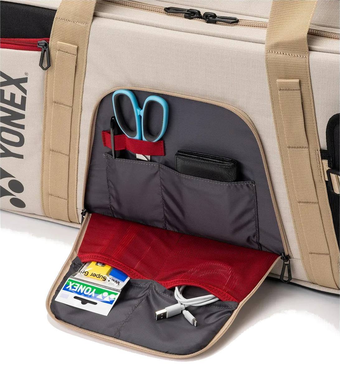 A close-up of an open side pocket on the Yonex BA72631WEX Gearlogic Tournament Badminton Bag in beige, displaying neatly organized compartments with scissors, a wallet, cards, a USB cable, and other small items inside.