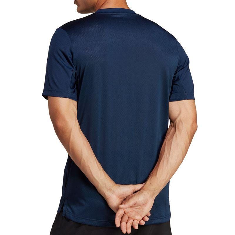 A person is seen from the back wearing a navy ADIDAS Mens Club Badminton T-Shirt by adidas, with hands clasped behind. The short-sleeved shirt harmonizes flawlessly with the plain white background, capturing both style and simplicity.
