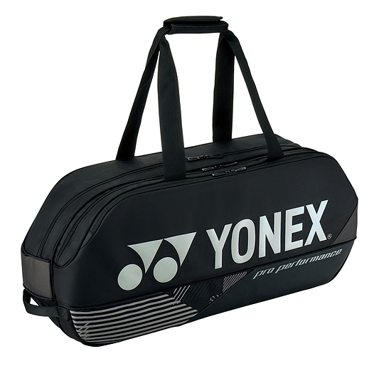 The Yonex 92431WEX Pro Tournament 6 Racket Badminton Bag in black features a large white Yonex logo and the words "pro performance" on the side. It is equipped with dual handles and designed to hold up to 6 rackets, showcasing a sleek design with a zippered main compartment and subtle striped accents at the bottom.