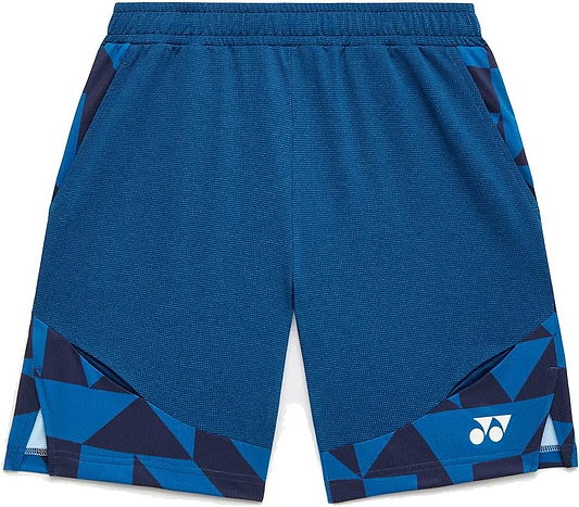 The Yonex 15240YX Knit Men's Badminton Shorts in Indigo Blue feature a geometric pattern, elastic waistband, side pockets, quick-dry fabric, and a white Yonex logo on the lower left leg.