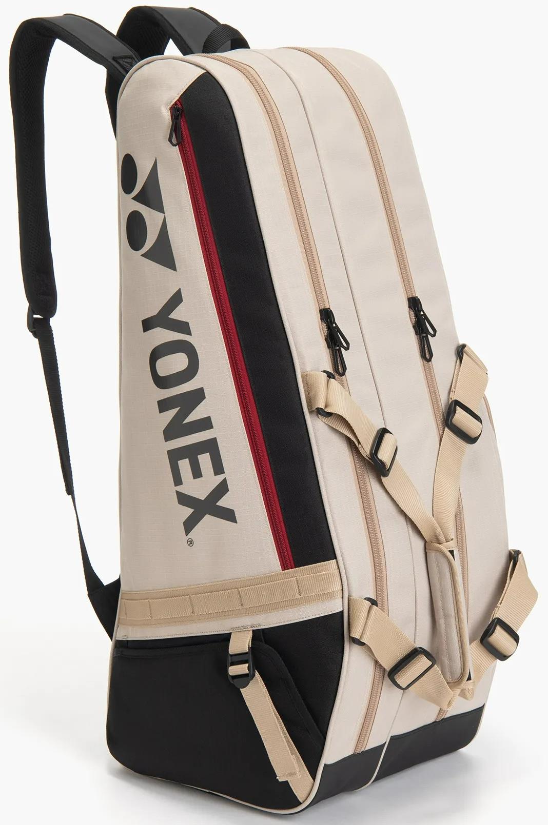 The Yonex BA72626EX Gearlogic 6 Racket Badminton Bag in beige features black and red accents, multiple zippered compartments, adjustable straps, recycled polyester material, and a Yonex logo on the side.