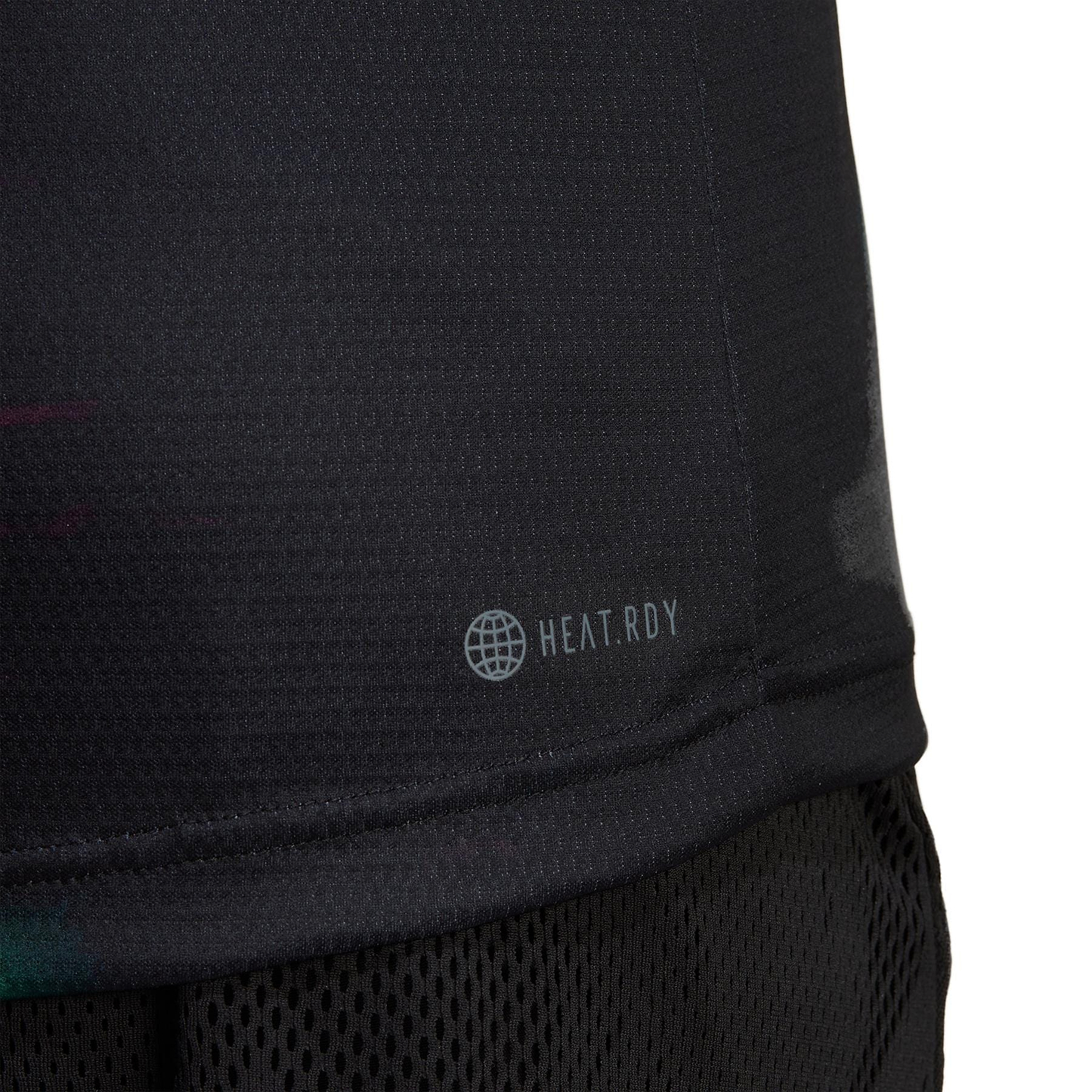 Close-up of an eco-friendly black athletic shirt, labeled with "HEAT.RDY" and a globe icon, crafted using sustainable carbon recycling. The adidas Melbourne Men's Freelift Polo Shirt features a textured, breathable design, perfectly paired with black mesh shorts.