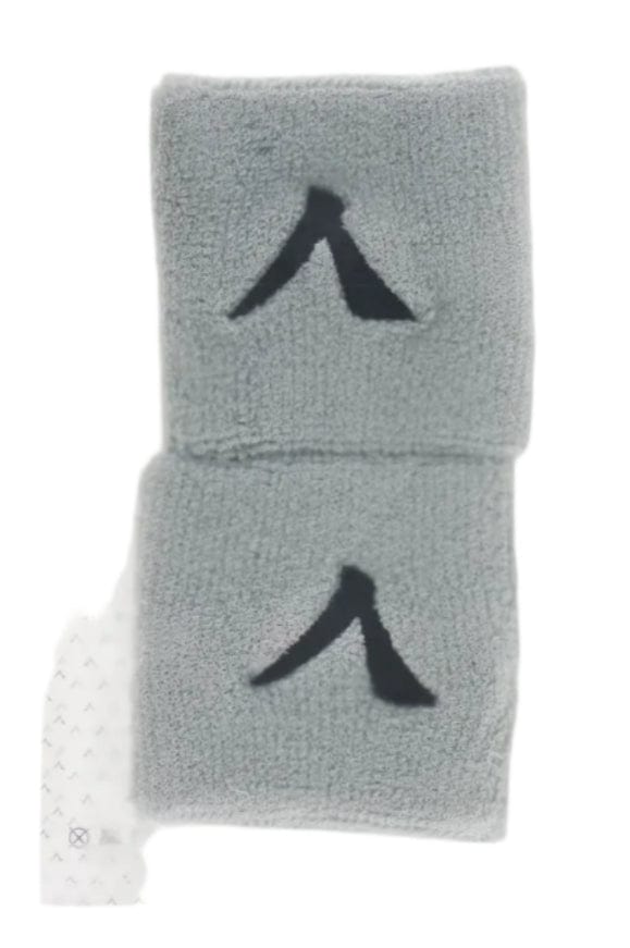 A sealed package contains a pair of gray wristbands designed for maximum comfort, each with a black abstract logo. The clear packaging has a white top label that reads "Kanso 7cm Wristband - 2 Pack - Grey" against a plain white background.
