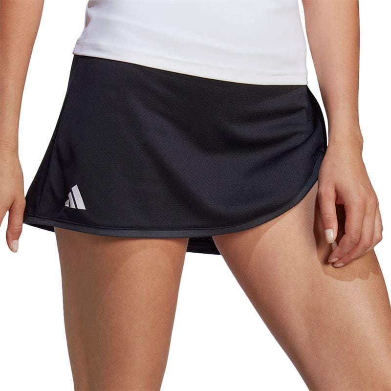 A person is wearing a black skirt featuring the adidas logo on the side, paired with a white top. The spotlight is on the ADIDAS Womens Club Badminton Skirt in Black, emphasizing its AEROREADY fabric and comfortable wide waistband for an exceptional fit and style.