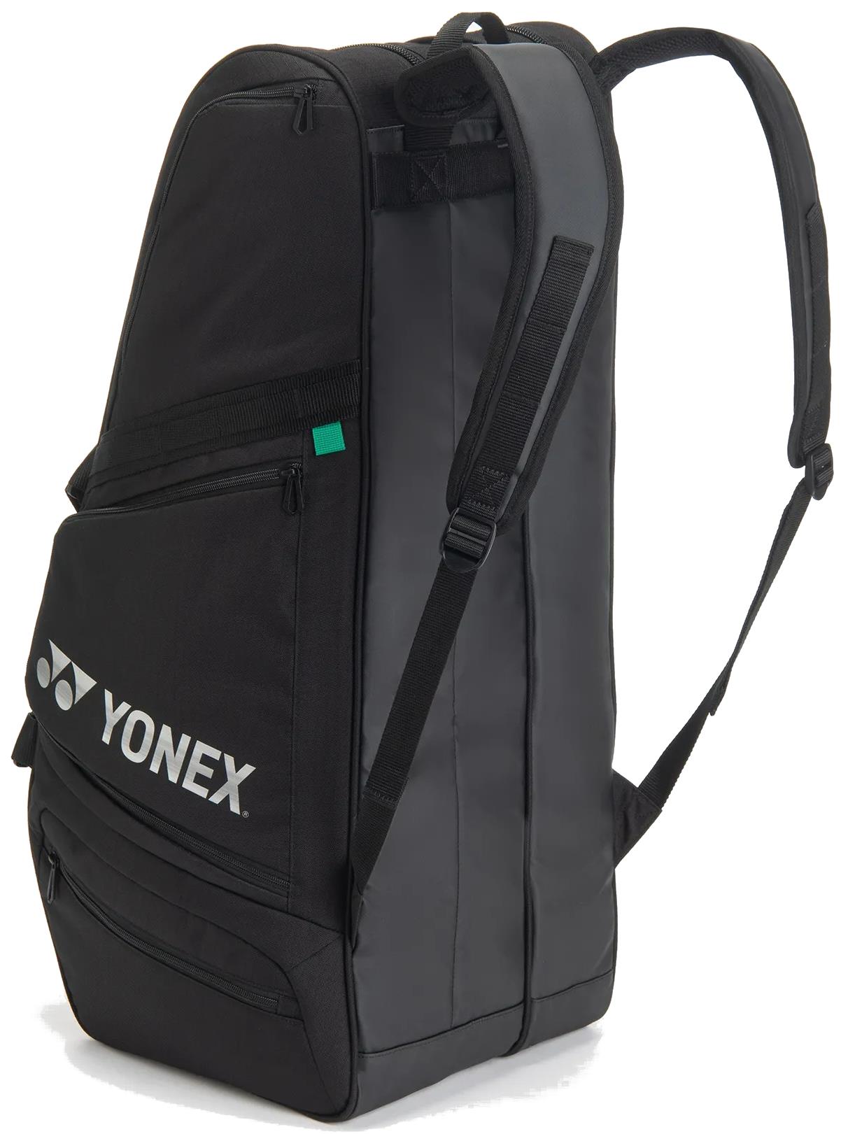 The Yonex BA72626EX Gearlogic 6 Racket Badminton Bag in black features padded shoulder straps, multiple zippered compartments, and a Yonex logo on the front pocket. Its upright angled design highlights both structure and style.
