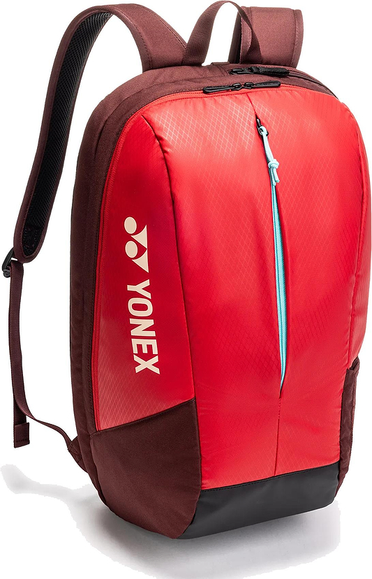 The Yonex 42512EX Team Badminton Backpack in Ruby Red features a front zipper pocket, blue zipper detail, adjustable shoulder straps, and a vertical Yonex logo on the side.
