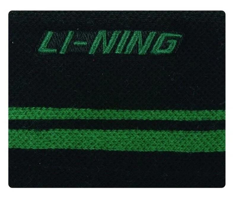 Close-up of the Li-Ning Logo Wristband in black with a breathable fabric design, featuring the brand's green logo embroidered at the top and two parallel horizontal green stripes. Ideal for badminton players seeking both style and comfort.