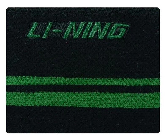 Close-up of the Li-Ning Logo Wristband in black with a breathable fabric design, featuring the brand's green logo embroidered at the top and two parallel horizontal green stripes. Ideal for badminton players seeking both style and comfort.