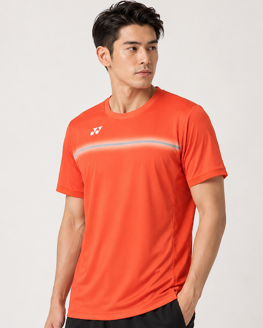A man stands against a plain light background, wearing the Yonex 10711YX Crew Neck Mens Badminton T-Shirt in Cyber Orange, featuring subtle horizontal stripes and a small white Yonex logo on the left chest.