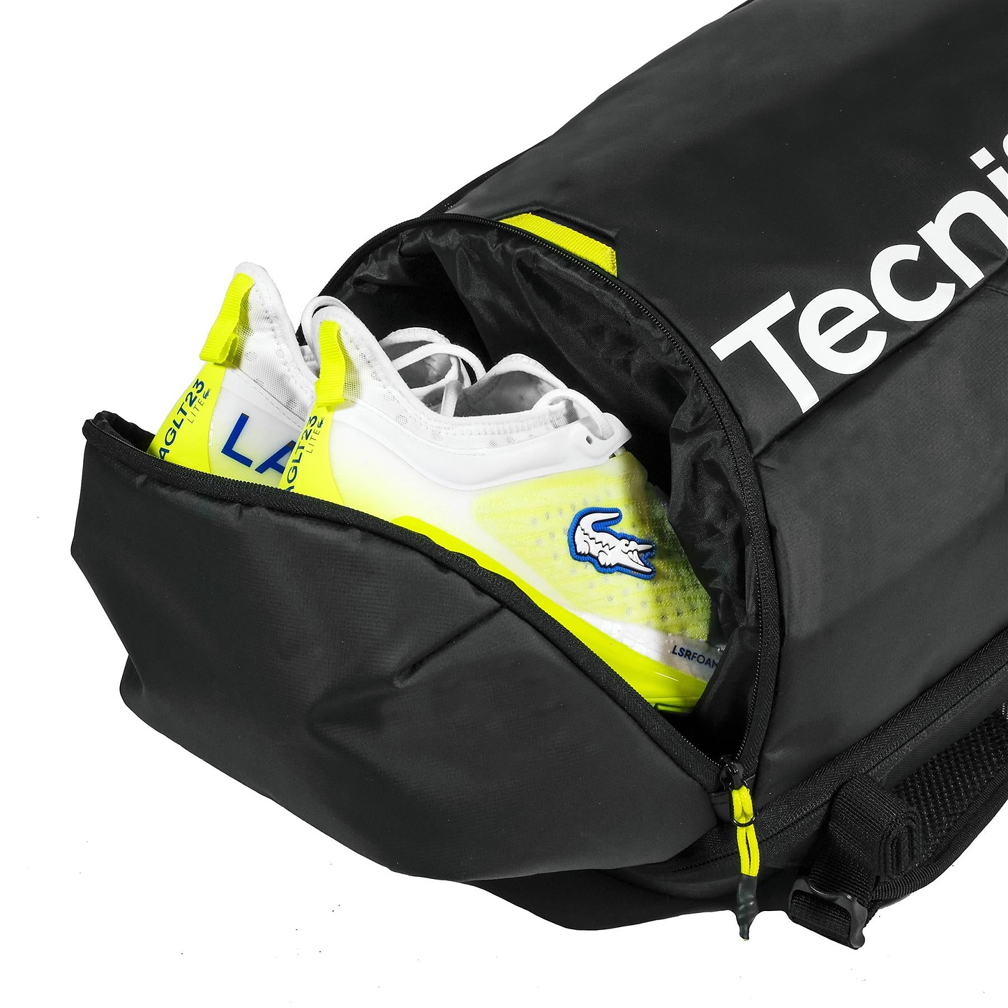 A pair of white and yellow sports shoes are partially packed in the end compartment of a black Tecnifibre Reform Badminton Backpack, featuring a zippered opening.