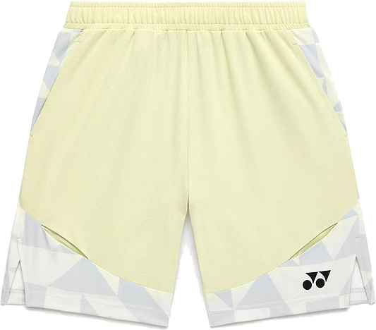 The Yonex 15240YX Knit Men's Badminton Shorts in Champagne feature a light yellow color with white and gray geometric accents, breathable fabric, elastic waistband, side pockets, and a small black Yonex logo on the lower left leg.