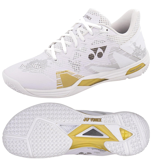 The Yonex Power Cushion Eclipsion Z3 Men's Badminton Shoes in white and gold feature a geometric upper design, textured grip sole with a central gold diamond for cushioning and repulsion, and the Yonex logo displayed on the tongue and side.