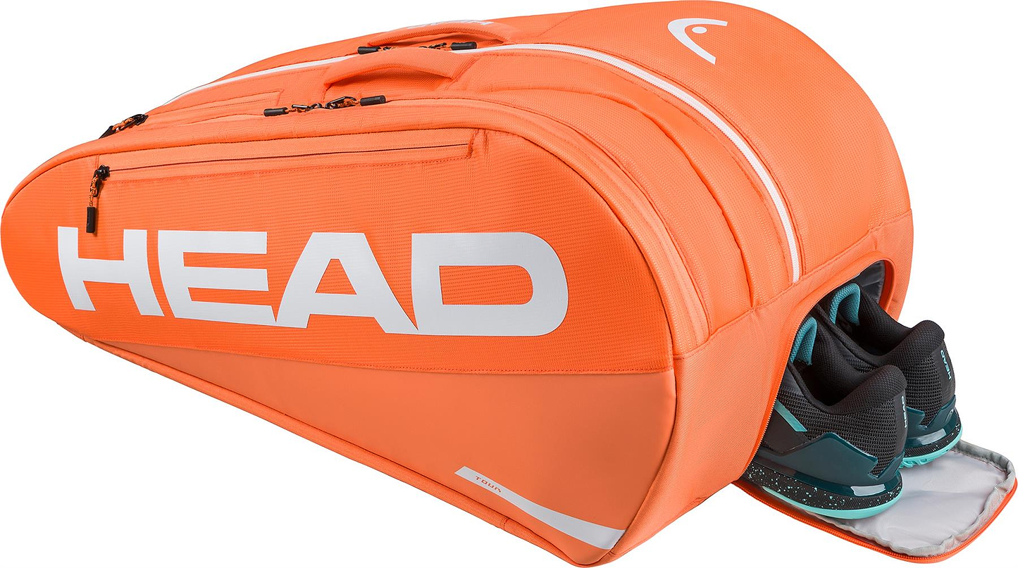 The HEAD Tour 12 Racket Badminton Bag XL in orange features multiple compartments and climate control technology; one pocket is partly open, revealing black and teal athletic shoes. The white HEAD logo stands out on the bag.