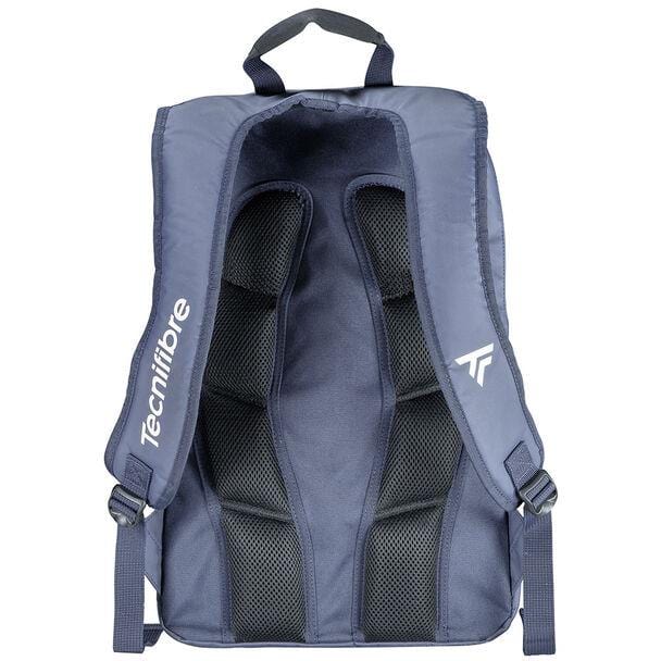 Back view of a navy blue backpack, constructed from durable tarpaulin fabric, featuring black padded straps with mesh padding for comfort. The brand name "Tecnifibre" is printed in white on the left strap, accompanied by a small logo on the right. This model, from the 2023 Tecnifibre Tour Endurance line, includes a top handle for easy carrying.