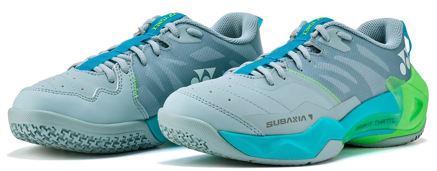 The Yonex Subaxia GT 2026 Women's Badminton Shoes in Grayish Green feature GRPHT THRTTL technology, a textured sole, blue laces, and Yonex branding on the sides and heel.