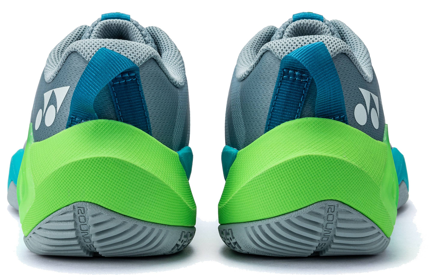 A pair of Yonex Subaxia GT 2026 Women's Badminton Shoes by Yonex, shown from the back in grayish green with blue and green accents, a textured GRPHT THRTTL sole, white heel logos, and visible heel tabs for easy wearing.