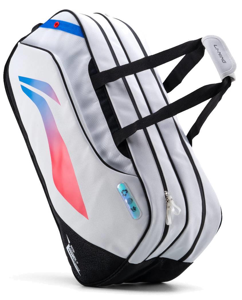 The Li-Ning Competition 6 Racket Badminton Bag in white and black features dual zippered compartments, sturdy black straps, a blue and red design, and "LI-NING" branding—ideal for stylishly carrying rackets to competitions.