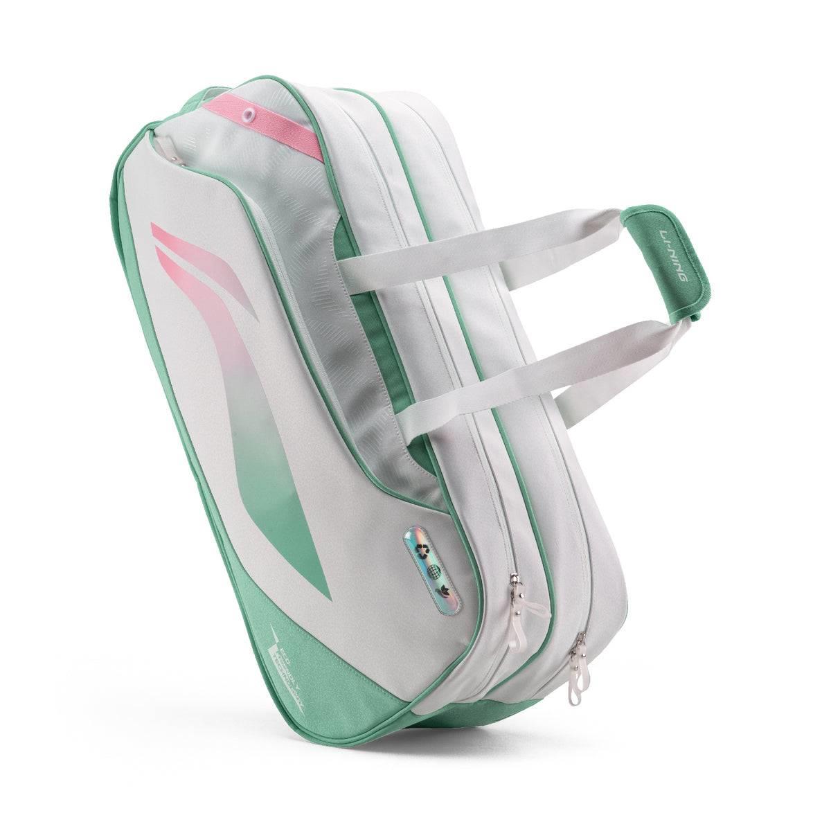 The Li-Ning Competition 6 Racket Badminton Bag in white and green features zippered compartments, two carry handles, and a modern design. The "Li-Ning" logo is visible on the handle and bottom corner.