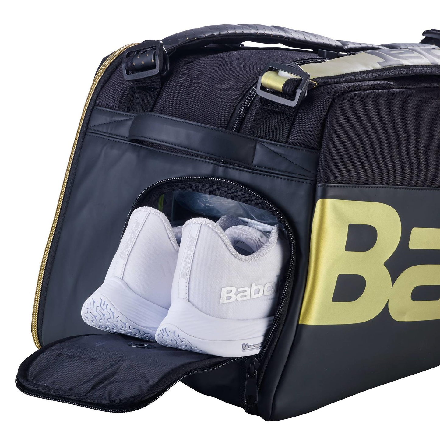 A pair of white sneakers are stored in the zippered side pocket of the Babolat Cross Pro Badminton Bag - Black / Gold by Babolat, with its thermoformed shell and partially open compartment revealing the shoes.