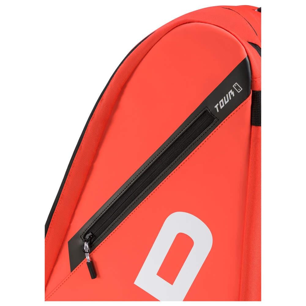 A close-up of the HEAD Tour Badminton Racket Bag XL in fluorescent orange showcases a black zippered side pocket with "TOUR" printed nearby. This versatile design, perfect for badminton rackets, ensures convenience with its backpack carry system.