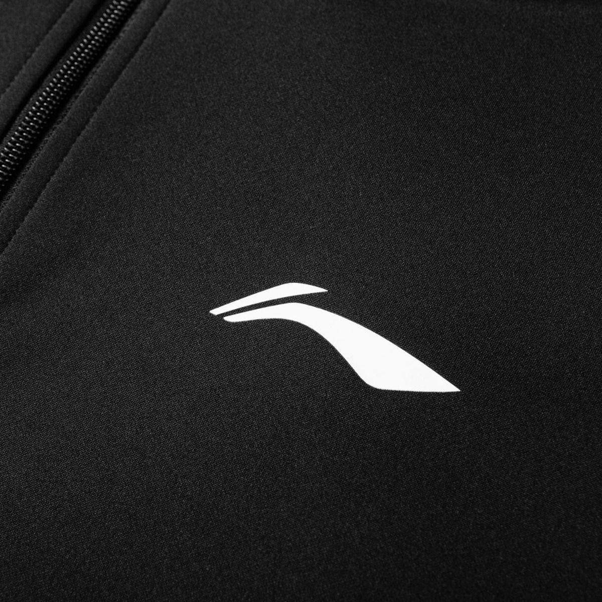 A close-up features black fabric from the Li-Ning Unisex Badminton Tracksuit Set, highlighted by a white abstract swoosh-like logo near the zipper. The smooth texture and minimalistic logo enhance this high-performance sportswear's sleek, modern aesthetic.