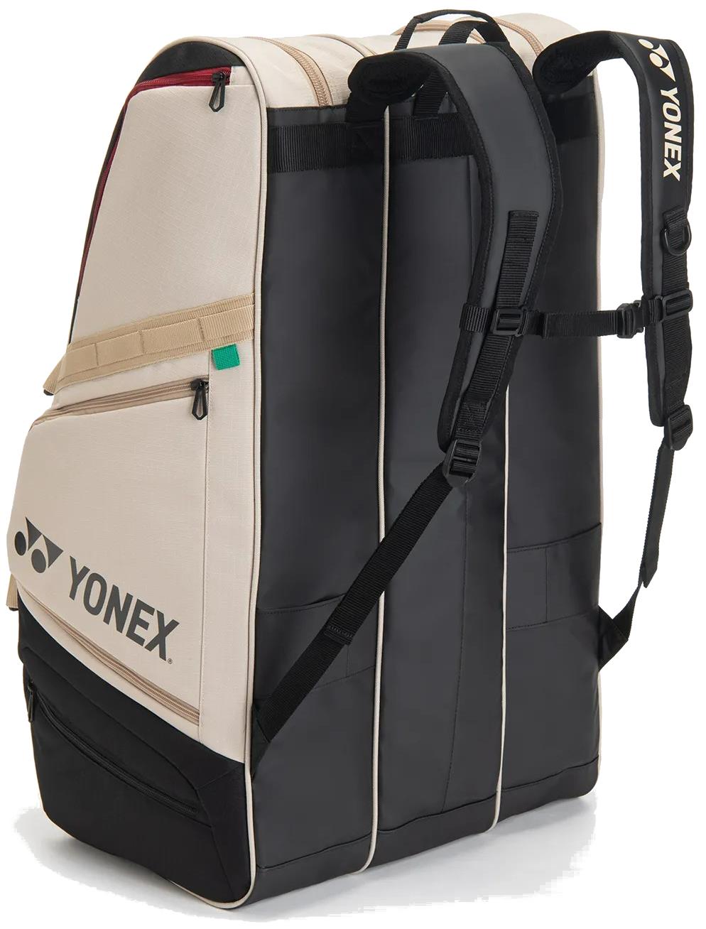 The Yonex BA726212EX Gearlogic 12 Racket Badminton Bag in beige features backpack straps, a side pocket, tan-black design, and Yonex logos; it holds up to 12 rackets plus gear for spacious storage.