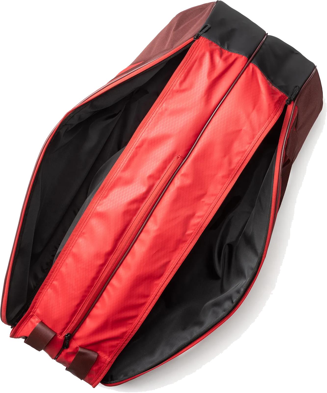The Yonex 42526EX Team 6 Racket Badminton Bag in Ruby Red features a spacious main compartment with black lining and dual zipper tracks, offering ample storage for up to six rackets—perfect for players needing extra space.