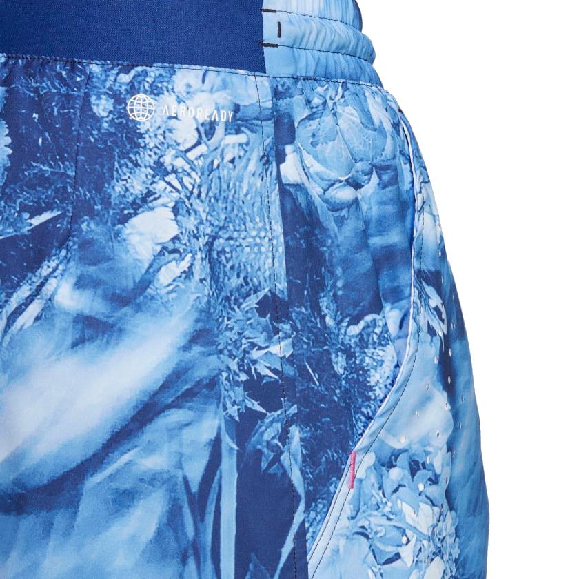 Close-up of the Victory Blue adidas Melbourne Men's Ergo Graphic Shorts, showcasing a white, abstract floral pattern and a subtle logo. Crafted from recycled materials, the design provides a textured and dynamic look.