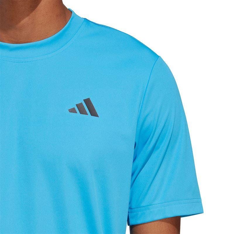 A man is seen wearing a pulse blue ADIDAS Men's Club Badminton T-Shirt, featuring a discreet logo on the chest. The photograph highlights the top half of this badminton shirt against a white backdrop.