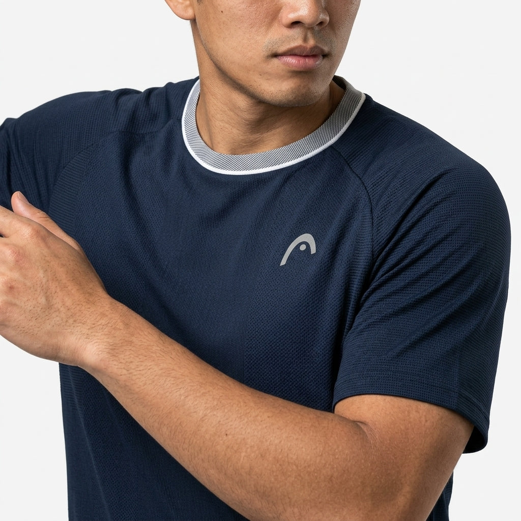 Wearing the HEAD Performance Mens Badminton T-Shirt - Navy, featuring a white collar trim and small logo, a man poses with one arm raised against a plain background—a stylish men's badminton apparel pick from HEAD.