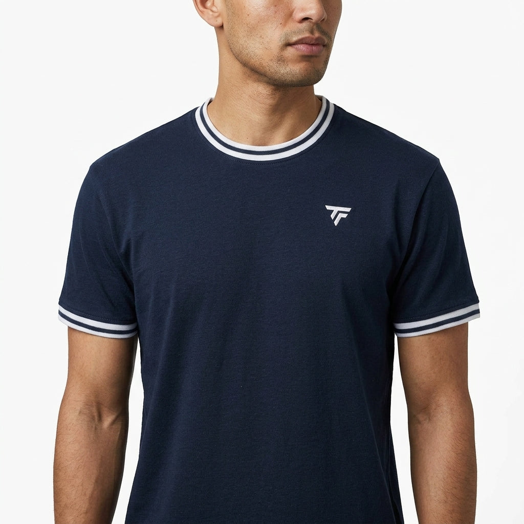 A man wearing a Tecnifibre Team Stretch Mens Badminton T-Shirt in Marine Blue with white trim and a small white chest logo stands against a plain white background.