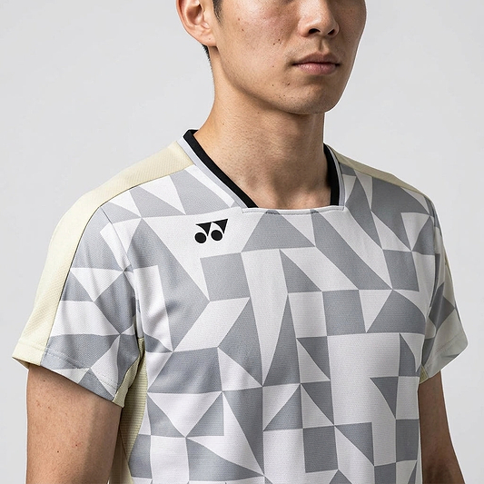 A man models the Yonex 10712YX Crew Neck Men's Badminton T-Shirt in Champagne, featuring a geometric gray-white design, small black chest logo, and quick-dry crew neck; shown from shoulders to mid-torso against a plain background.