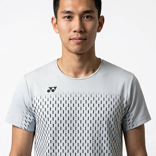 A young man with short dark hair wears the Yonex 10713EX Crew Neck Men's Badminton T-Shirt in silver grey, featuring a moisture-wicking geometric pattern and small black Yonex logo, standing against a plain white background.