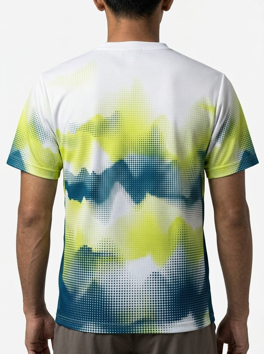 A person with short dark hair is seen from behind wearing a Yonex YTM2025A Mens Badminton T-Shirt - White by Yonex, showcasing a digital pixelated gradient design in yellow, green, blue, and white on performance fabric.