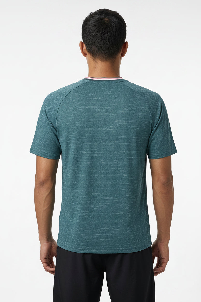 A man with short black hair stands with his back to the camera, wearing a K-Swiss Hypercourt Mens Melange 3 Badminton T-Shirt in Stargazer and black shorts against a plain white background.