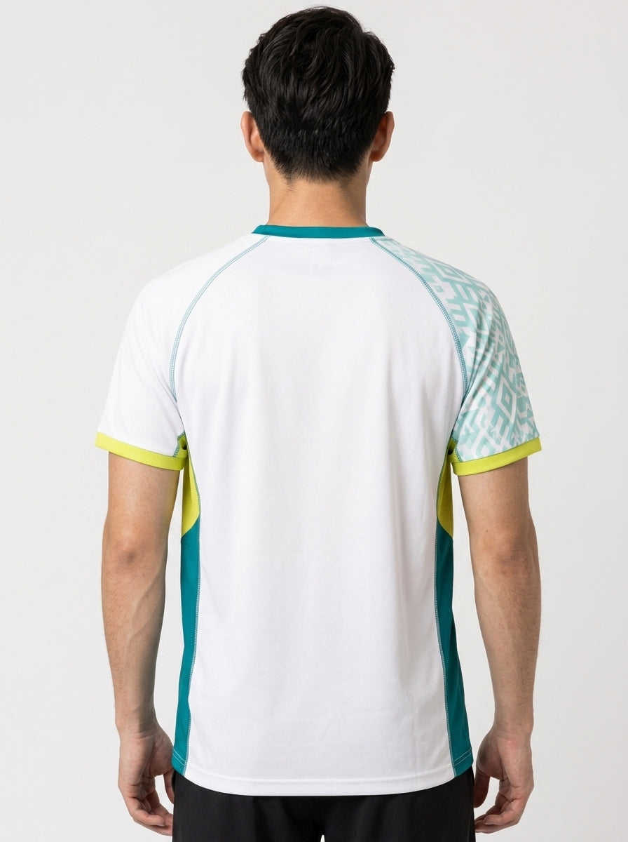 A man is seen from behind wearing the Yonex YTM11 Mens Badminton T-Shirt in white, featuring teal side panels, yellow accents, and a patterned teal and white section on one shoulder.