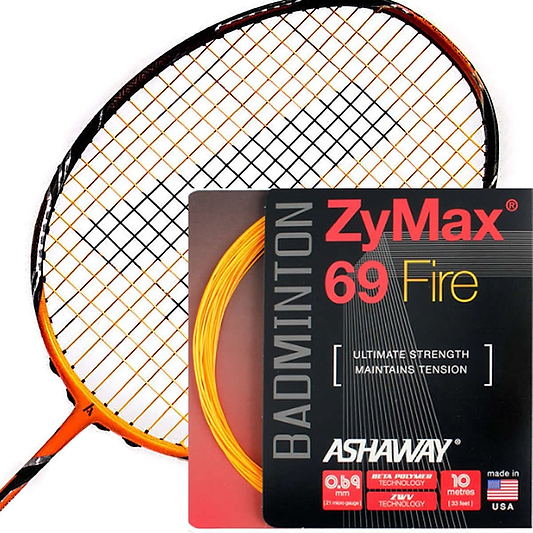 A badminton racket with orange and black strings is displayed next to a pack of Ashaway Zymax 69 Fire Badminton Strings in an eye-catching red and gray design. The packaging emphasizes the string's ultimate strength, durability, and excellent tension maintenance for prolonged string life.